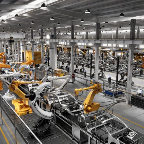 Robotic arms assemble car frames on a production line in a modern automotive manufacturing factory.